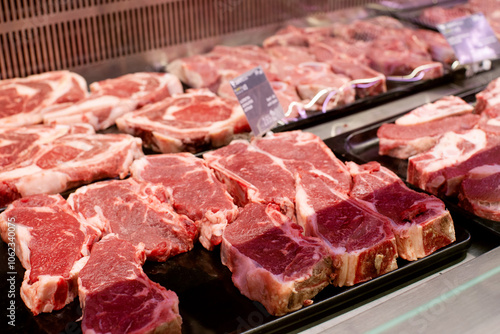 Raw beef and pork cuts of meat into steaks behind the glass of the refrigerator on the counter in the supermarket