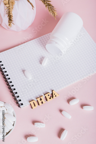 Hormonal supplements in a bowl, notebook and bottle on pink background vertical view