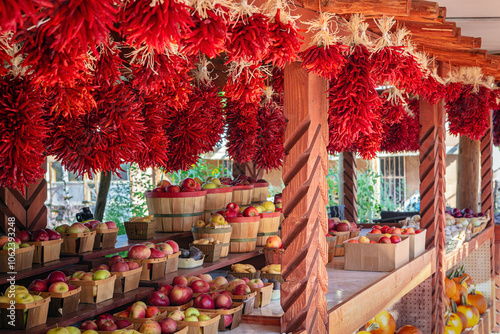 Outdoor vegetable stand with baskets of fruit and red chili pepper ristras hanging from the top in Toas New Mexico, USA. 