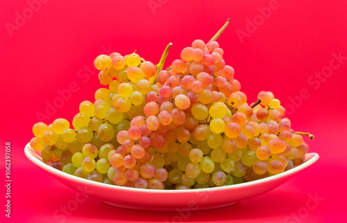 Obraz na płótnie Plate with kishmish (sultana) grapes on a red background w salonie