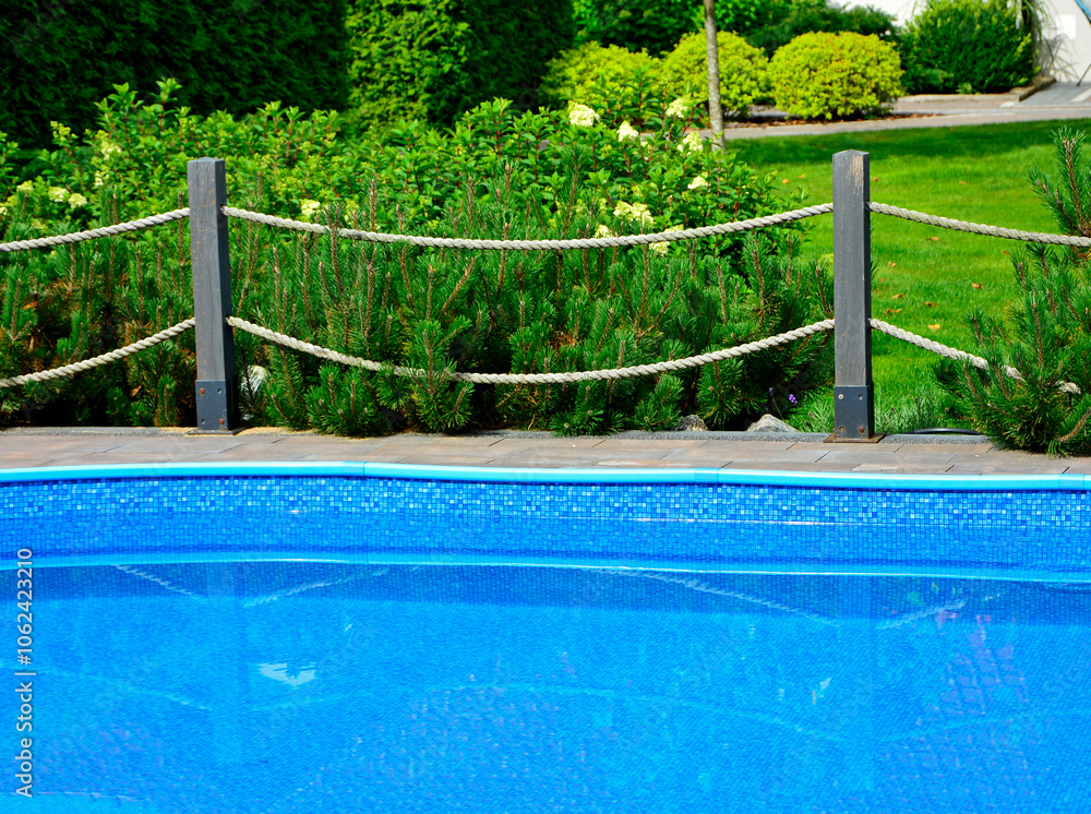 błekitna woda w ogrodowym basenie otoczonym drewnianym płotkiem i sznurami, blue water in the garden swimming pool with a fence and ropes