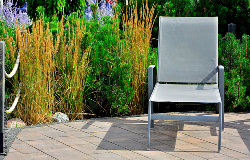 Obraz na płótnie szary leżak w ogrodzie, leżak ogrodowy, puste leżaki ogrodowe, gray deckchair in the garden, garden deckchair, empty garden sunbeds, sitting area w salonie