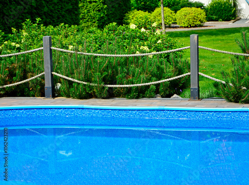 Obraz na płótnie błekitna woda w ogrodowym basenie otoczonym drewnianym płotkiem i sznurami, blue water in the garden swimming pool with a fence and ropes
w salonie