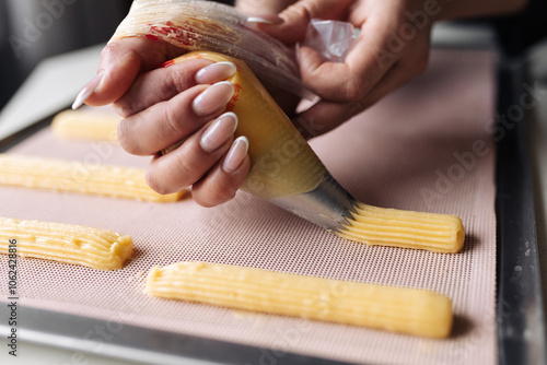 Squeeze the dough out of the pastry bag o nto a baking tray for baking eclairs.