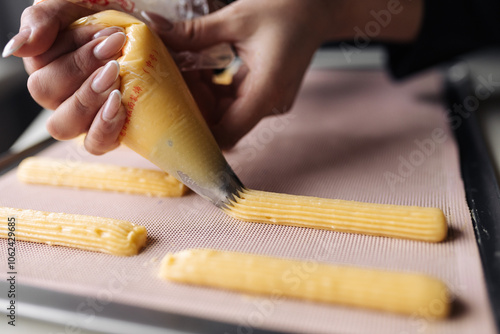 Squeeze the dough out of the pastry bag o nto a baking tray for baking eclairs.