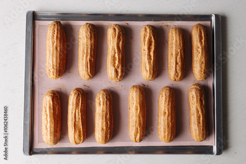 golden brown eclairs on a pink baking sheet