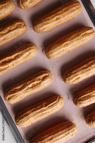 golden brown eclairs on a pink baking sheet