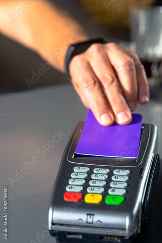 Person tapping credit card on payment terminal for contactless payment photo