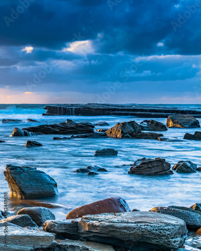 Moody sunrise seascape with clouds at the rocky inlet