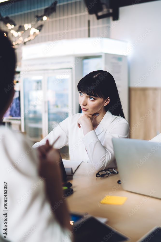Concentrated multiracial colleagues discussing project and using laptop in meeting room