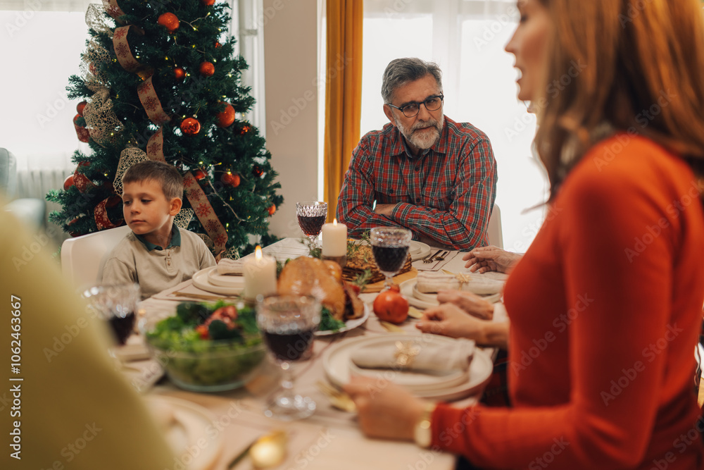 Family sitting at table enjoying christmas dinner together Family sitting at table enjoying christmas dinner together
