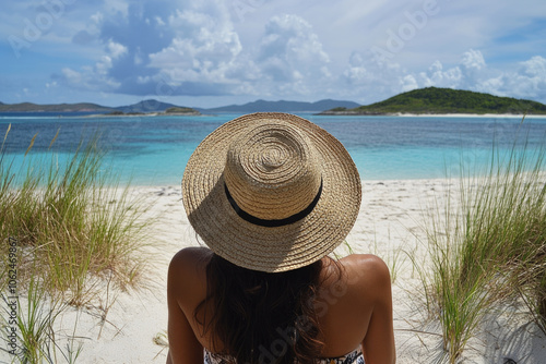 The serene image shows a woman from behind, wearing a wide-brimmed sunhat, gazing at the tranquil ocean, enveloped in the peaceful beauty of nature. photo