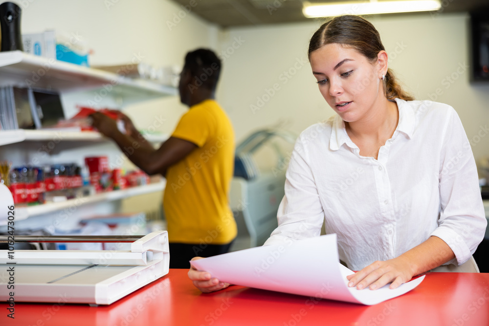 Fototapeta premium Portrait of an attentive woman checking quality of printing in a printing house