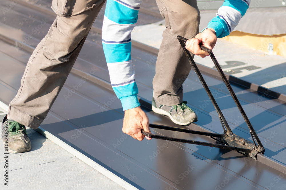 Roofer assembles sheet metal on the roof. Construction workers - installation assembly of new roof. Roofing tools. Roofer assembles sheet metal on the roof. Construction workers - installation assembly of new roof. Roofing tools.