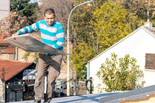 Roofer assembles sheet metal on the roof. A worker repairing the roof of a home. Roofing