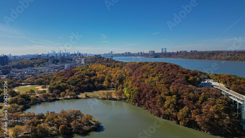 This location in the Bronx offers stunning views of lush greenery, a picturesque lake, and urban structures. Framed by the river, it showcases iconic bridges and the New York City skyline in the dista