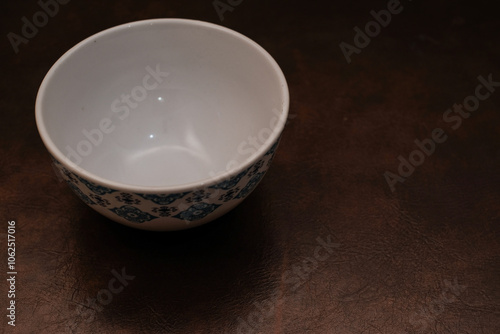 A empty blue pattern ceramic bowl with white inside isolated on brown background, Blue porcelain ceramic bowl.