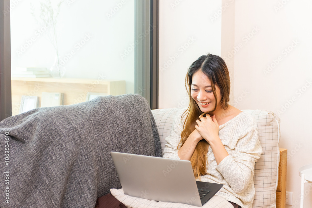 Naklejka premium Happy Asian woman freelance celebration success business project after working on laptop computer at home. Businesswoman remote working online corporate business and video conference in living room.