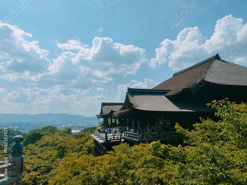 Majestic Kiyomizu-dera temple set amidst rich foliage, viewed from a striking angle with cloudy skies, symbolizing tradition and tranquility with an expansive outlook.