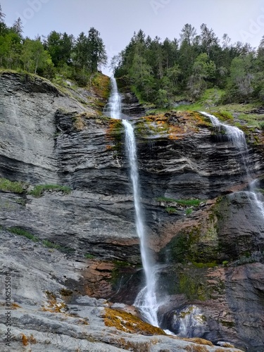 A breathtaking waterfall cascading down majestic rocky cliffs surrounded by lush greenery, capturing the power and serenity of nature in perfect balance.