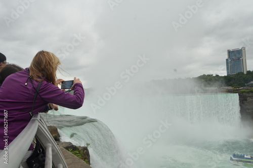 Stunning closeup view of rushing water and mist by Niagara Falls, Tourist taking photos Niagara River in Canada and New York. American Side, Canadian Side. Gorgeous nature, one  of the seven wonders. 