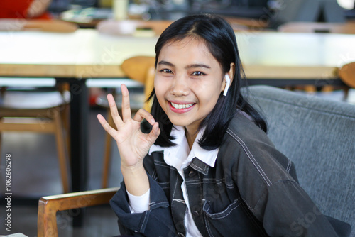 smiling asian woman show okay signs with excitement sitting in cafe, look at camera