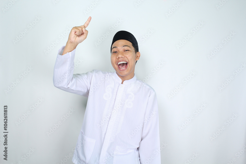 attractive muslim asian man pointing to above and shouting with mouth open isolated on white background attractive muslim asian man pointing to above and shouting with mouth open isolated on white background