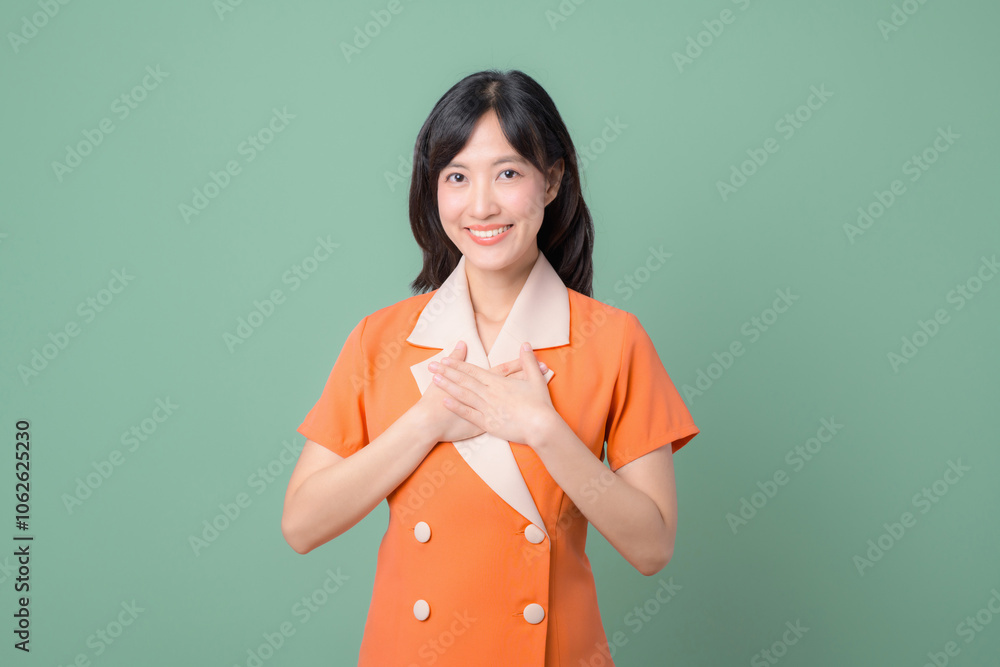 Φωτογραφία A young woman stands against a green background wearing an orange dress with white accents