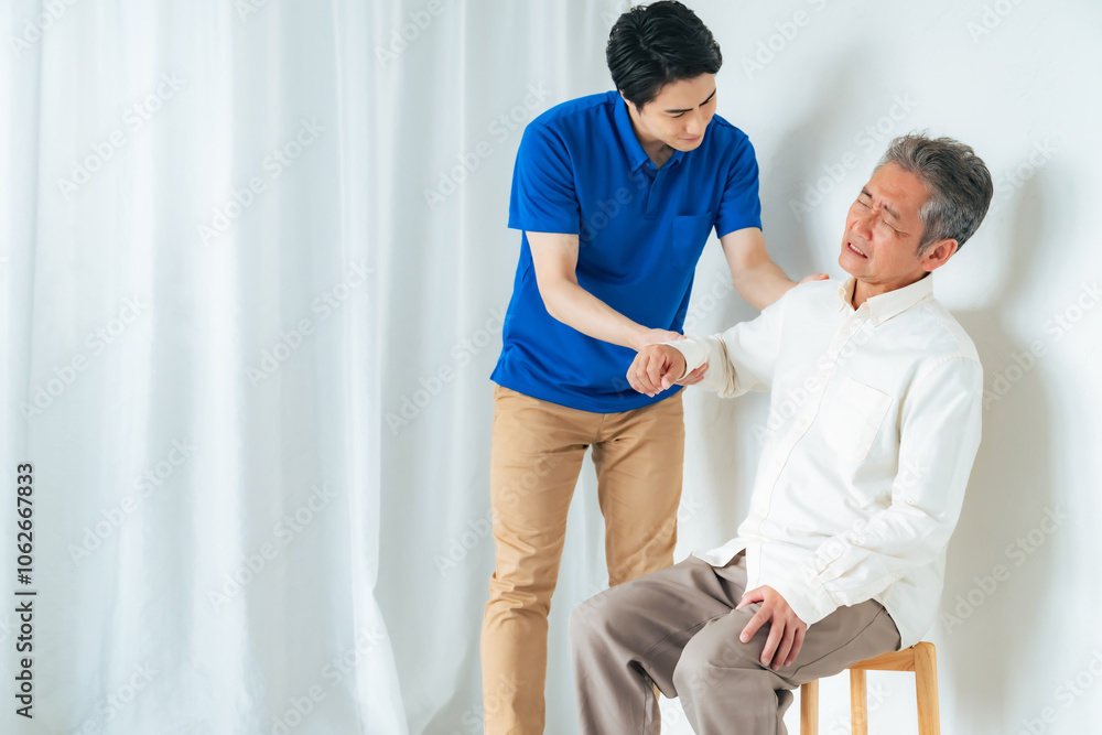 Obraz premium マッサージ、ストレッチ、リハビリ、肩、肩痛、トレーナー、五十肩、治療、関節、患者、男性、日本人、高齢者、四十肩、シニア、中高年、お年寄り、老人、ケアスタッフ、ヘルパー、相談、診断、診療、理学療法士、整体、整体師、診察、介護士、介護、肩関節周囲炎、ローテーターカフ損傷、肩峰下滑液包炎、肩こり、加齢、老化、リハビリテーション、インナーマッスル、トレーニング、腱板損傷、肩蜂下インピンジメント症候群、痛み