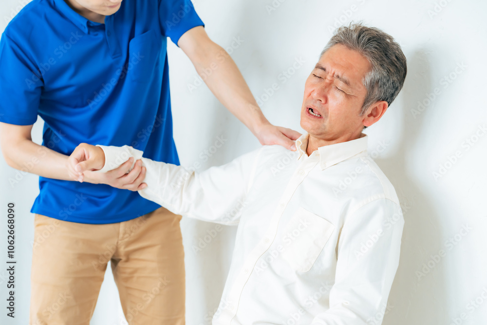 Obraz premium マッサージ、リハビリ、ストレッチ、肩痛、五十肩、治療、治療院、高齢者、シニア、中高年、肩、トレーナー、関節、患者、笑顔、男性、日本人、四十肩、お年寄り、老人、ケアスタッフ、ヘルパー、相談、診断、診療、理学療法士、整体、整体師、診察、介護士、介護、肩関節周囲炎、ローテーターカフ損傷、肩峰下滑液包炎、肩こり、加齢、老化、リハビリテーション、インナーマッスル、トレーニング、腱板損傷、肩蜂下インピンジメン