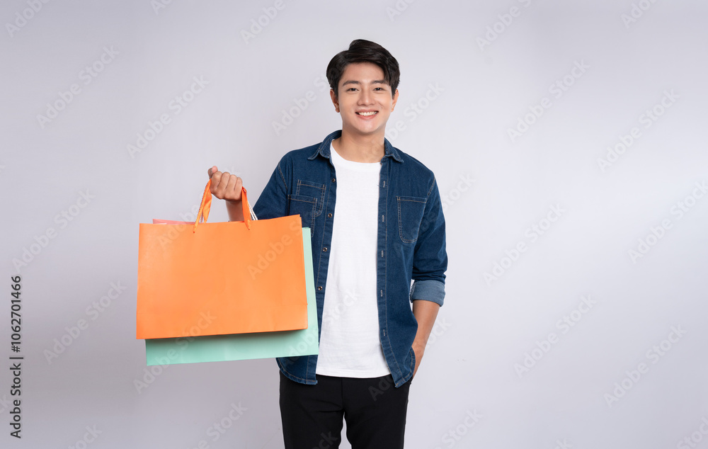 Portrait of young Asian man holding a shopping bag and posing on a white background Portrait of young Asian man holding a shopping bag and posing on a white background