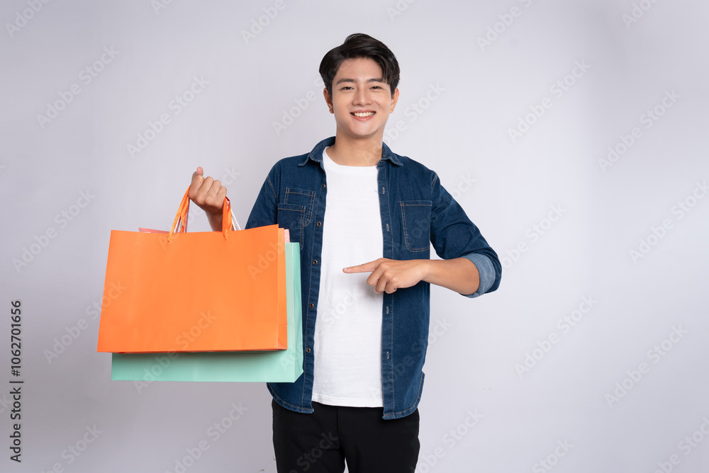 Portrait of young Asian man holding a shopping bag and posing on a white background Portrait of young Asian man holding a shopping bag and posing on a white background