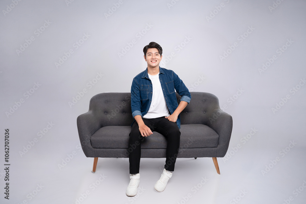 Full body image of young Asian man posing on sofa on white background Full body image of young Asian man posing on sofa on white background