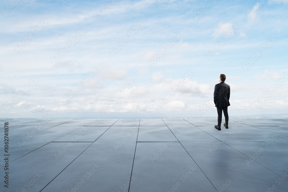 Man in business suit standing on a rooftop with a vast sky and clouds above. Man in business suit standing on a rooftop with a vast sky and clouds above.