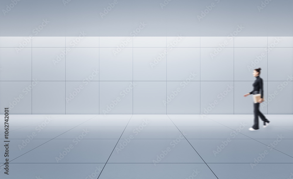 Person walking across a minimalist grey tiled room with abstract wall design and grey background. Person walking across a minimalist grey tiled room with abstract wall design and grey background.