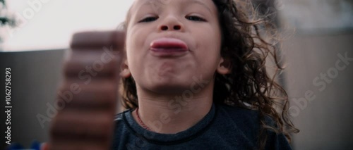 Latino little boy plays on playground and eats ice cream curly hair happy enjoys time outdoors