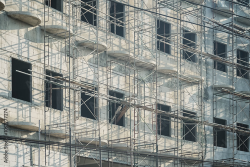 Extensive scaffolding providing platforms for work in progress on a new apartment block,Tall building under construction with scaffolds,Construction Site of New Building