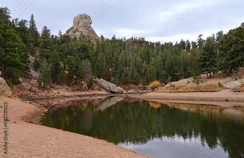 
hiking  through the forest along the middle crow creek shoreline in curt gowdy state park, southern wyoming, on a cloudy winter day, with a granite rock formation in the background photo