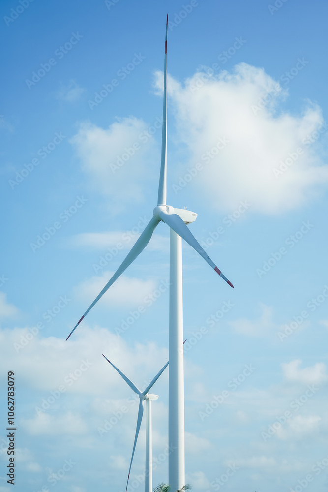 A large wind turbine for generating electricity using the force of the wind installed in an agricultural field against a blue sky. A large wind turbine for generating electricity using the force of the wind installed in an agricultural field against a blue sky.