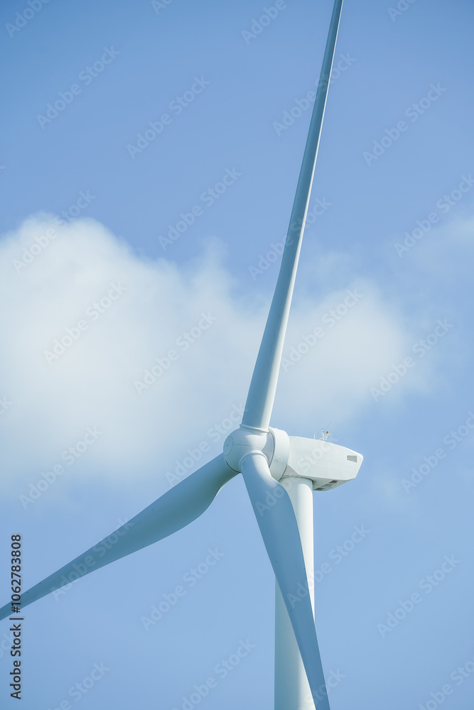 A large wind turbine for generating electricity using the force of the wind installed in an agricultural field against a blue sky. A large wind turbine for generating electricity using the force of the wind installed in an agricultural field against a blue sky.