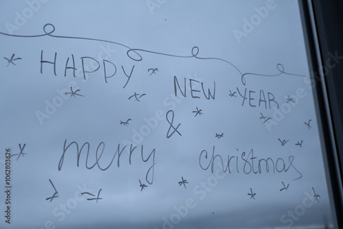 Sustainable responsible holiday decor. HAPPY NEW YEAR AND MERRY CHRISTMAS message painted on window glass indoor at home. Christmas winter decoration. White pattern. Snow art tracery on season. Diy photo