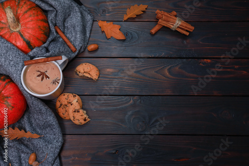 Pumpkin spicy latte, autumn hot drink, scarf and spices on dark brown wooden table. Cozy decoration for autumn coffee shop concept, thanksgiving celebration flat lay wit h copy space
