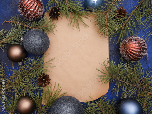 Craft paper with blank copy space for Christmas greeting card text in frame of festive baubles, pine fir tree branches. Winter holiday, New Year celebration concept. Top view, flat lay