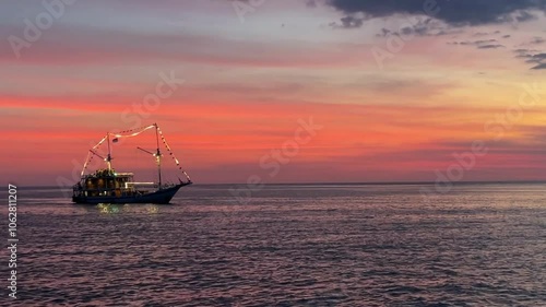 A tranquil sunset silhouettes pinisi schooner sailing in the beautiful sunset time. Good for nature and tourism footage photo