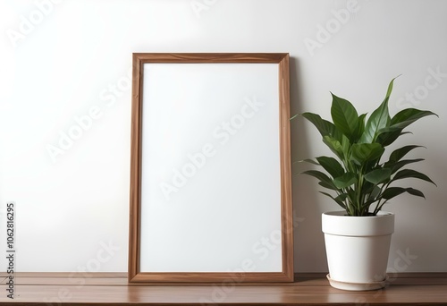 A wooden frame with a blank white canvas, placed on a wooden surface next to a potted plant