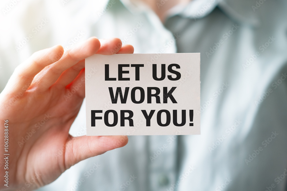 A person is holding a piece of paper that says Let us Work for You. A person is holding a piece of paper that says Let us Work for You.