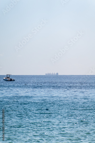 Calm blue sea with the silhouette of a large ship on the horizon