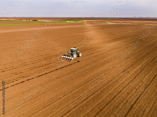 Tractor seeding crops in plowed field, agriculture industry