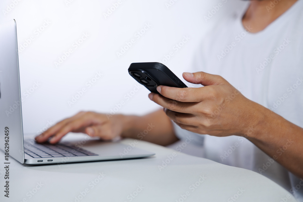 Middle-aged man in white shirt using laptop and smartphone on white background Middle-aged man in white shirt using laptop and smartphone on white background