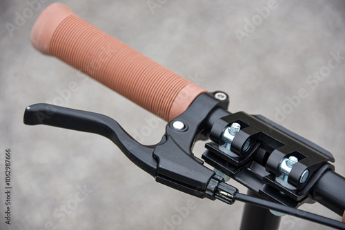 Brake lever on the scooter handlebar with beige handle.